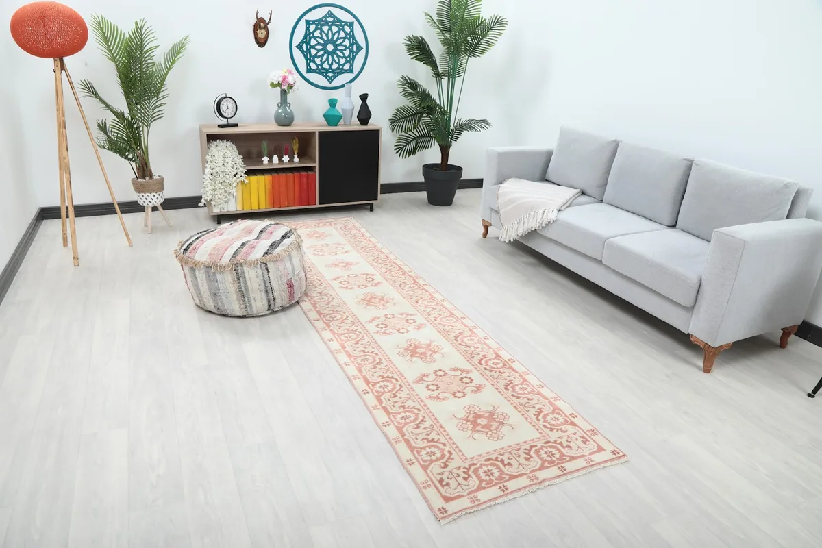 Overhead view of the runner rug in a room, highlighting its rose and ivory colors and geometric design.