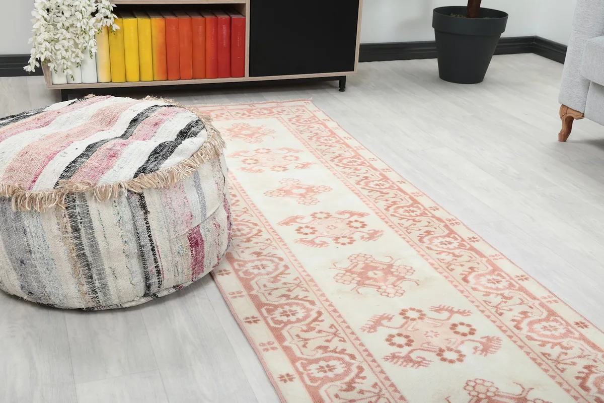 Close-up view of the runner rug's pattern and texture next to a striped ottoman in a room setting.
