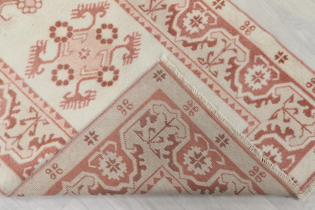 Folded corner of the rug revealing the cotton foundation and the reverse side of the hand-knotted wool pile.