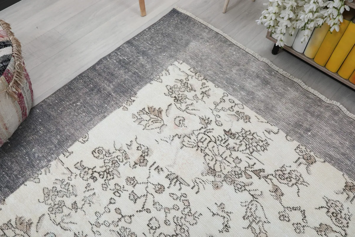 Angled view highlighting the corner and border of the ivory floral rug