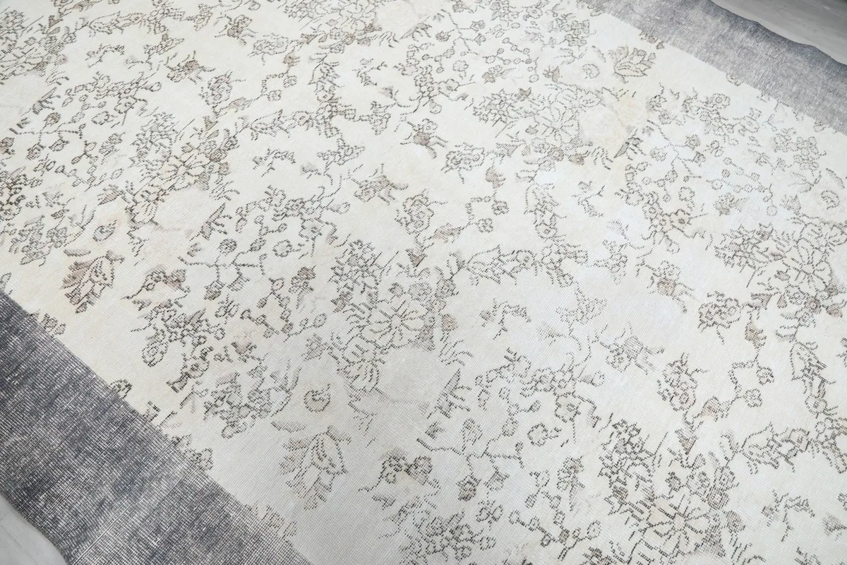 Close-up view of the detailed floral motifs on the ivory field of the rug