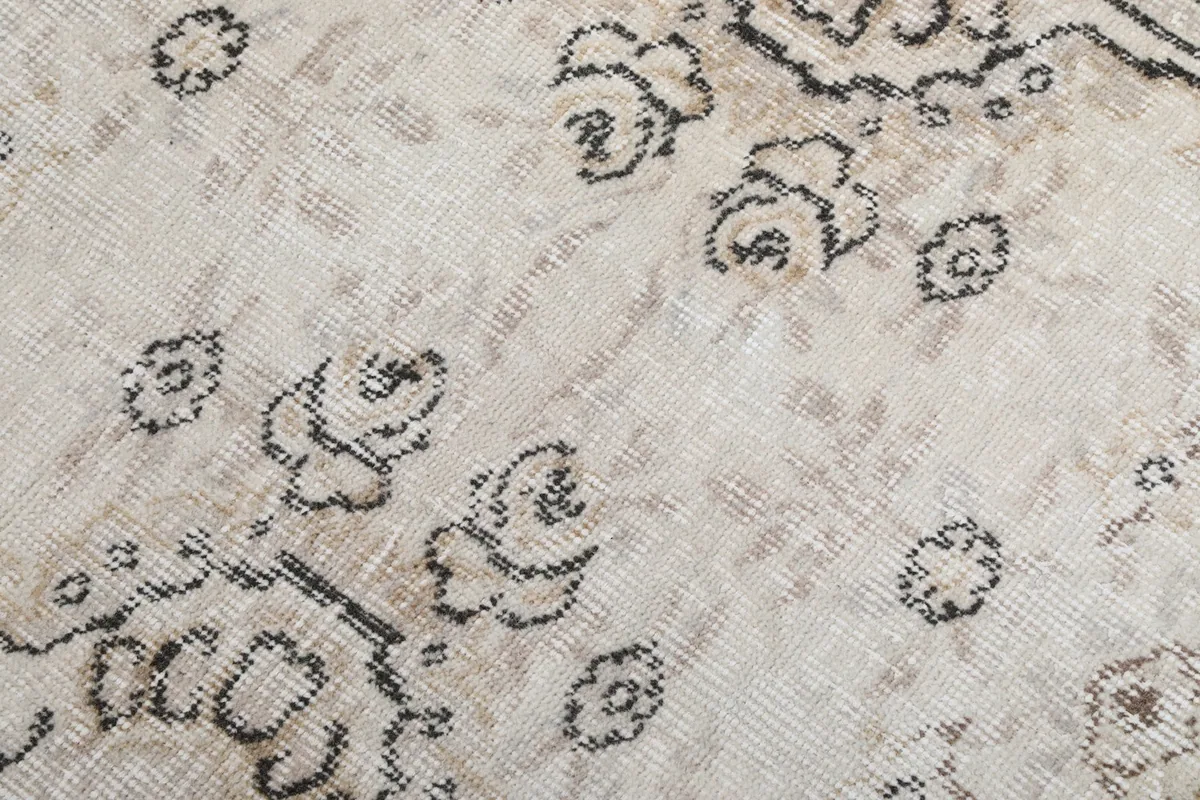 Close-up of the hand-knotted wool pile and intricate charcoal floral elements