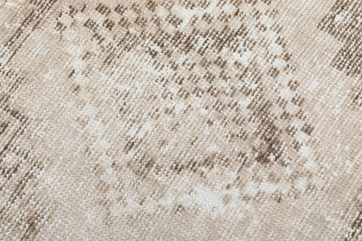 Texture of the low wool pile, showing the hand-knotted weave and distressed areas