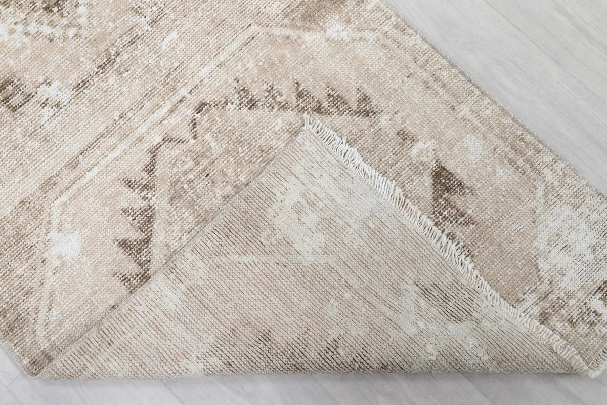 Underside of the rug folded over, revealing the cotton foundation and knotting
