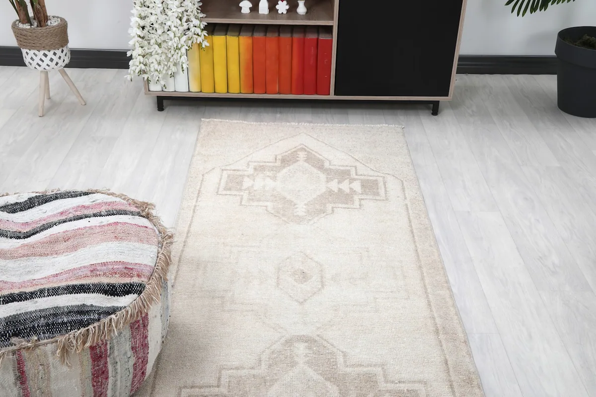 View of the rug extending from a striped ottoman towards a cabinet, highlighting its placement.