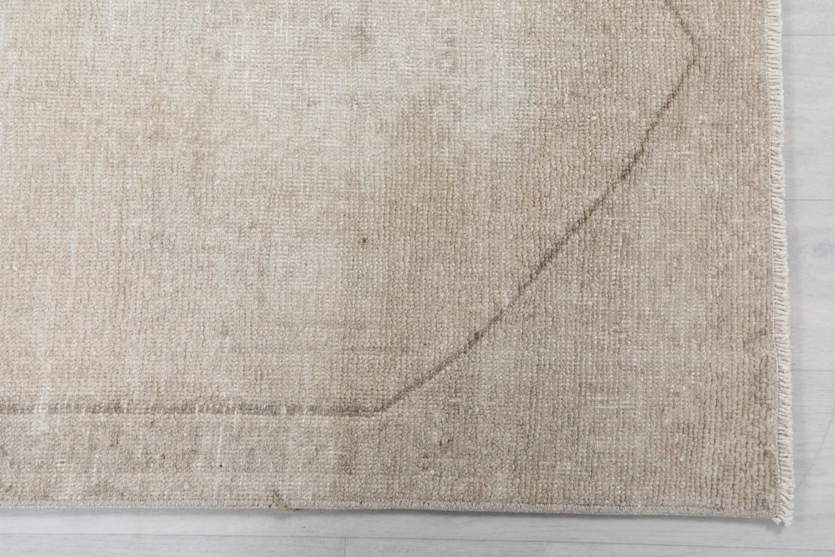 Close-up detail of the rug's corner, showing the subtle tan border and low pile texture.
