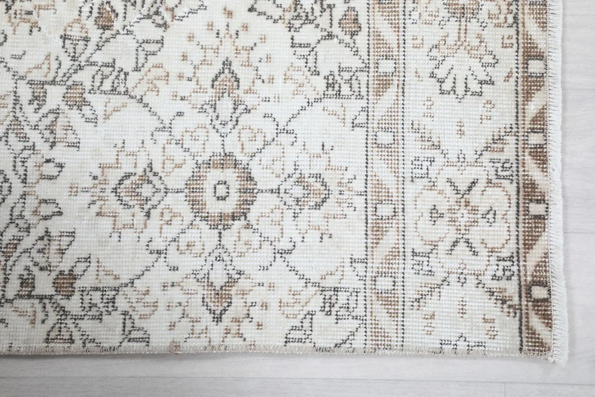 Detail of the rug's border design and field pattern, showing the hand-knotted wool pile.