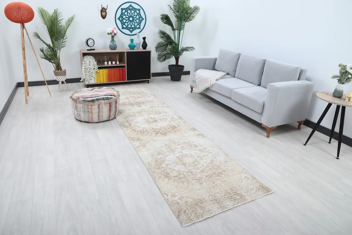 Long beige runner rug extending through a contemporary living area with a sofa and ottoman.