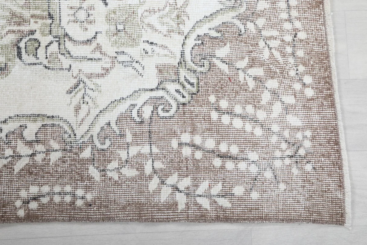 Detailed view of the rug's outer beige border with delicate patterns