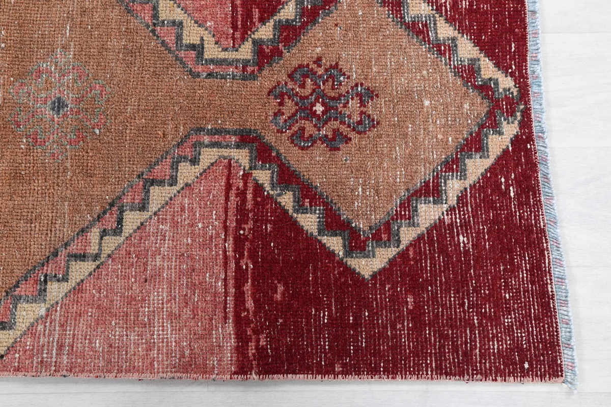 Close-up of the deep red and orange sections of the runner rug, showing wear and knotting