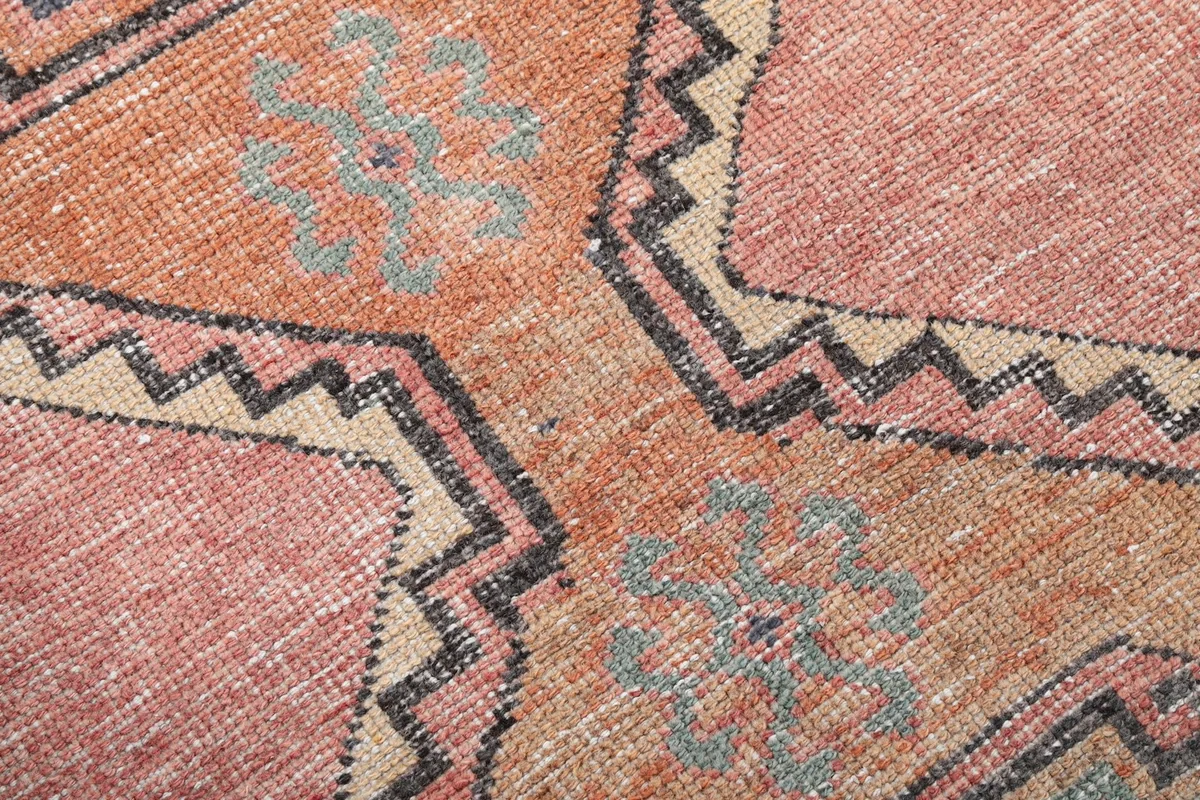 Close-up of the hand-knotted wool pile and intricate tribal motifs in beige and black