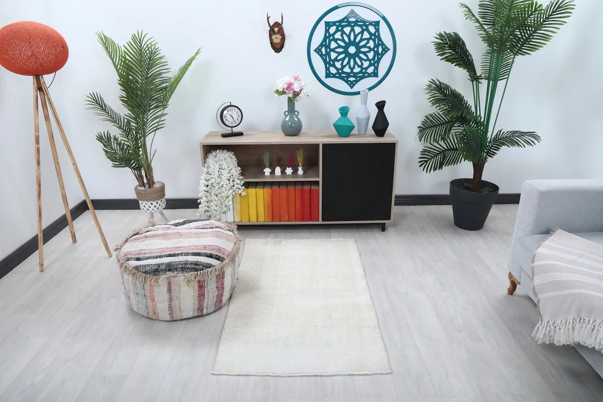 Ivory vintage rug placed in a modern living space with a light gray couch and wooden cabinet.