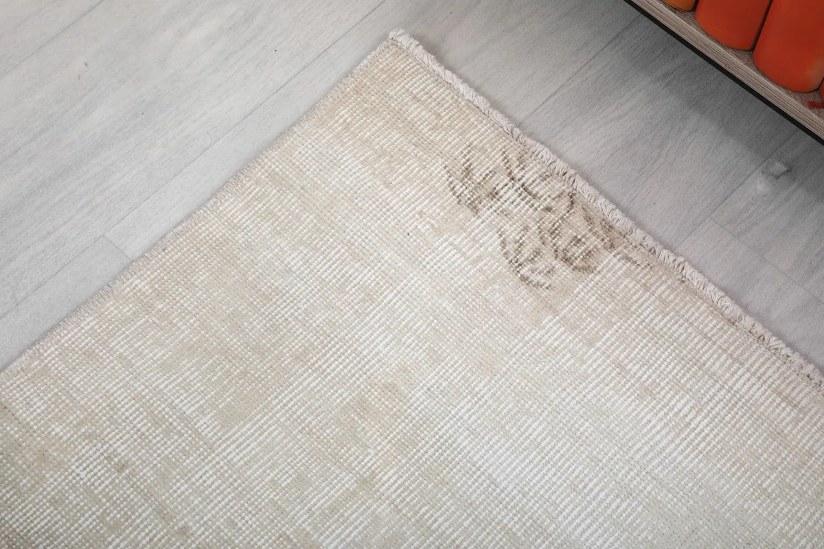 Detailed view of a subtle brown patch, showcasing the rug's natural vintage patina and character.
