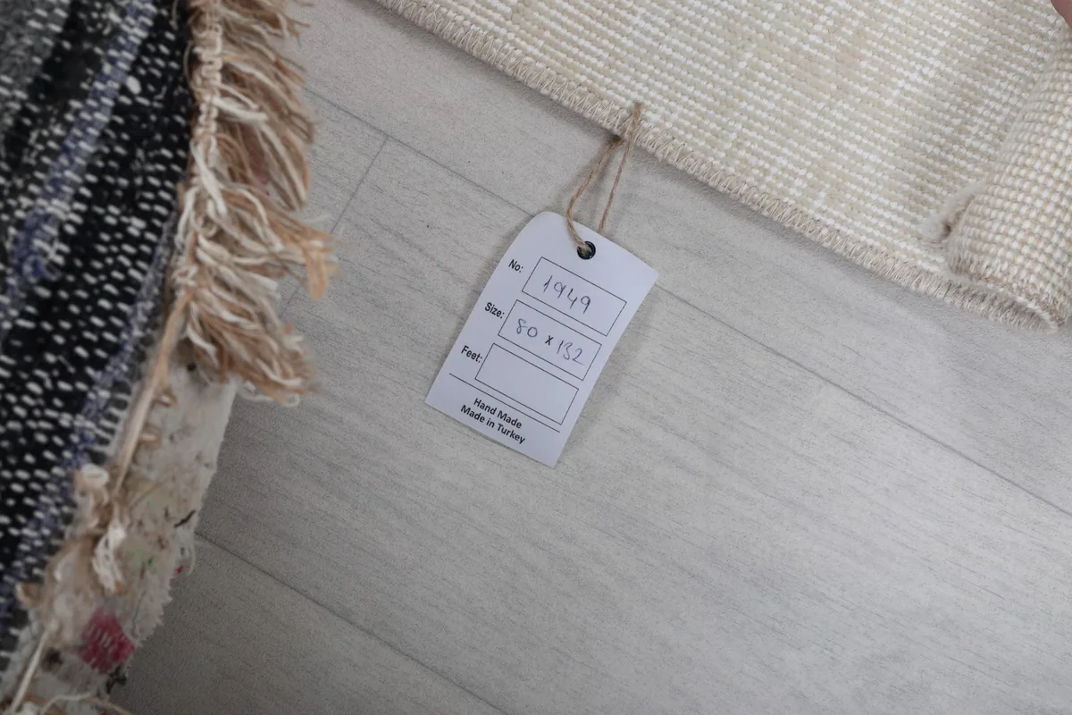 Rug tag displaying product information, confirming hand-knotted origin and material.