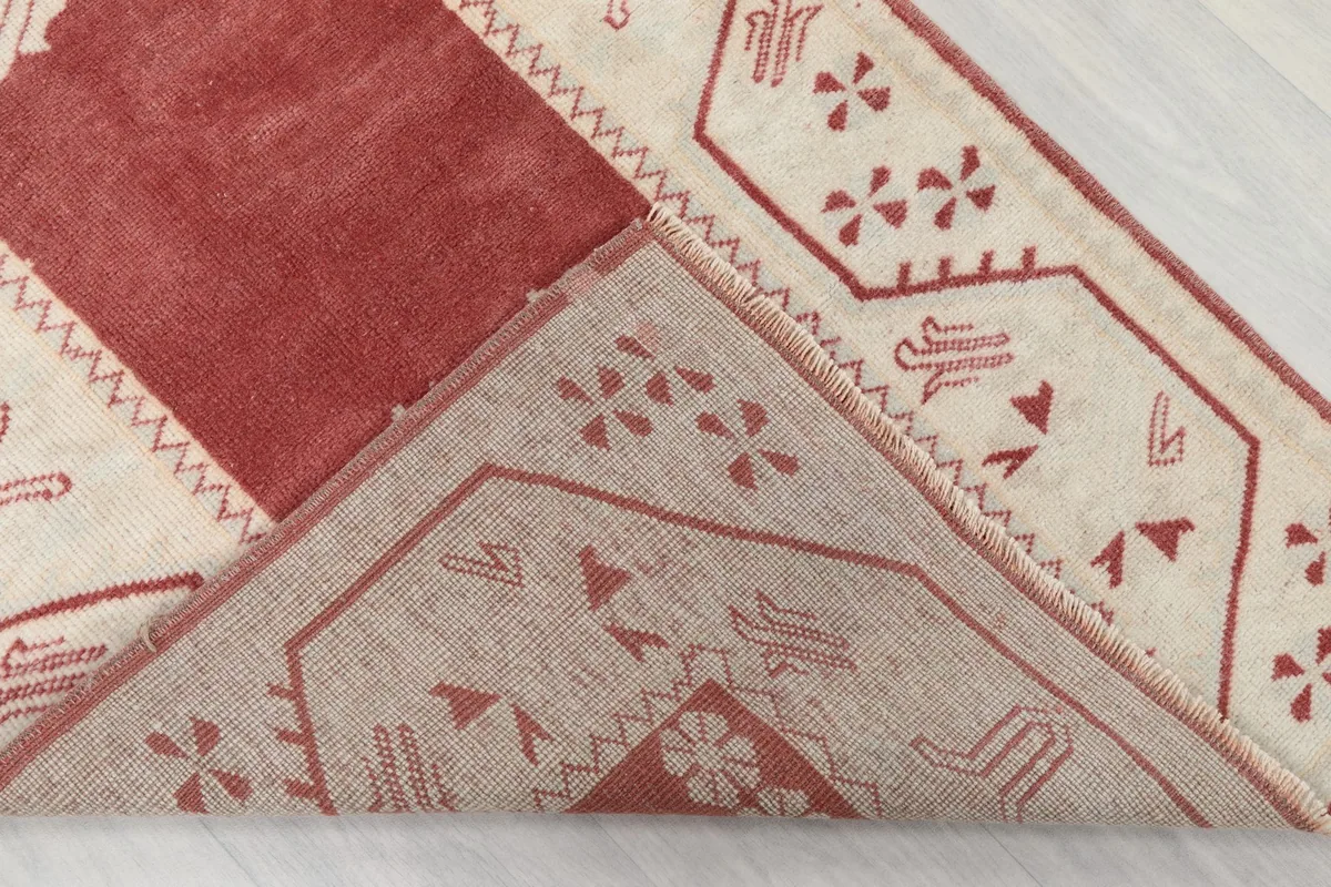 Partial view of the rug's underside, revealing the hand-knotted cotton foundation