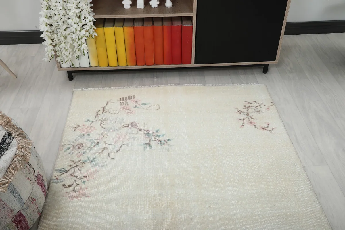 Overhead view of the rug in a room setting, highlighting the floral motifs and soft ivory color