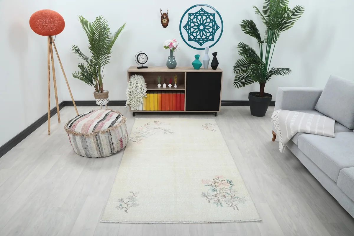 Ivory vintage Anatolian rug displayed in a living room setting with a light gray sofa and wooden furniture
