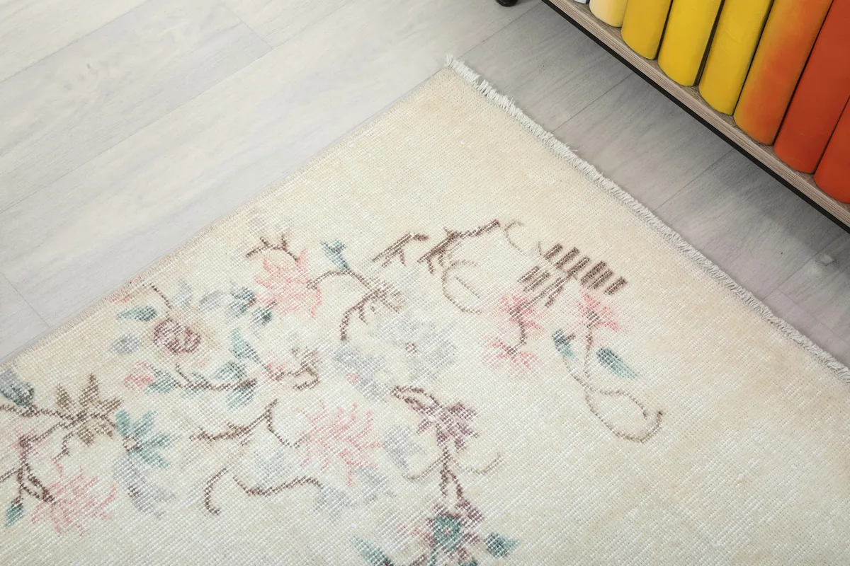 Detailed view of the upper left corner motif, showing the delicate pink and green blossoms