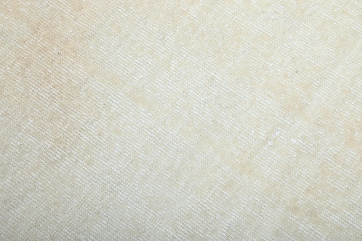 Close-up of the low wool pile and subtle texture of the ivory field of the vintage rug