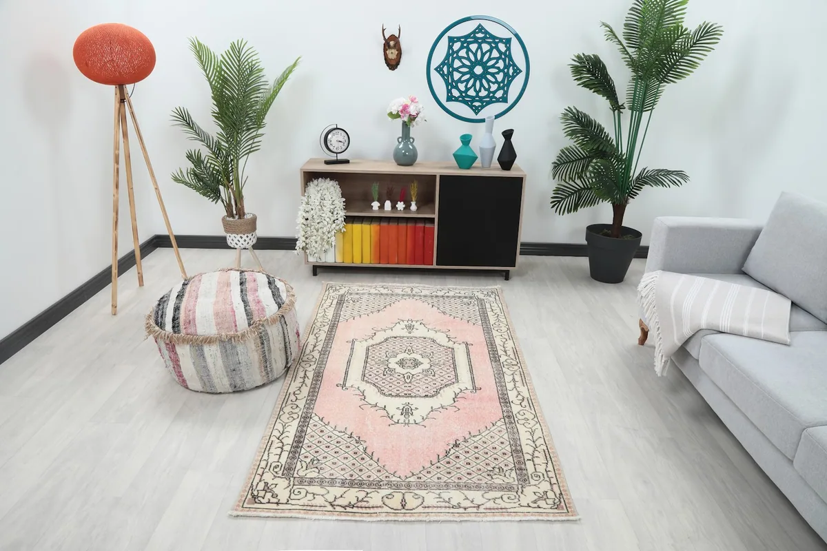 Vintage pink and ivory rug showcased in a modern living room setting with plants and furniture
