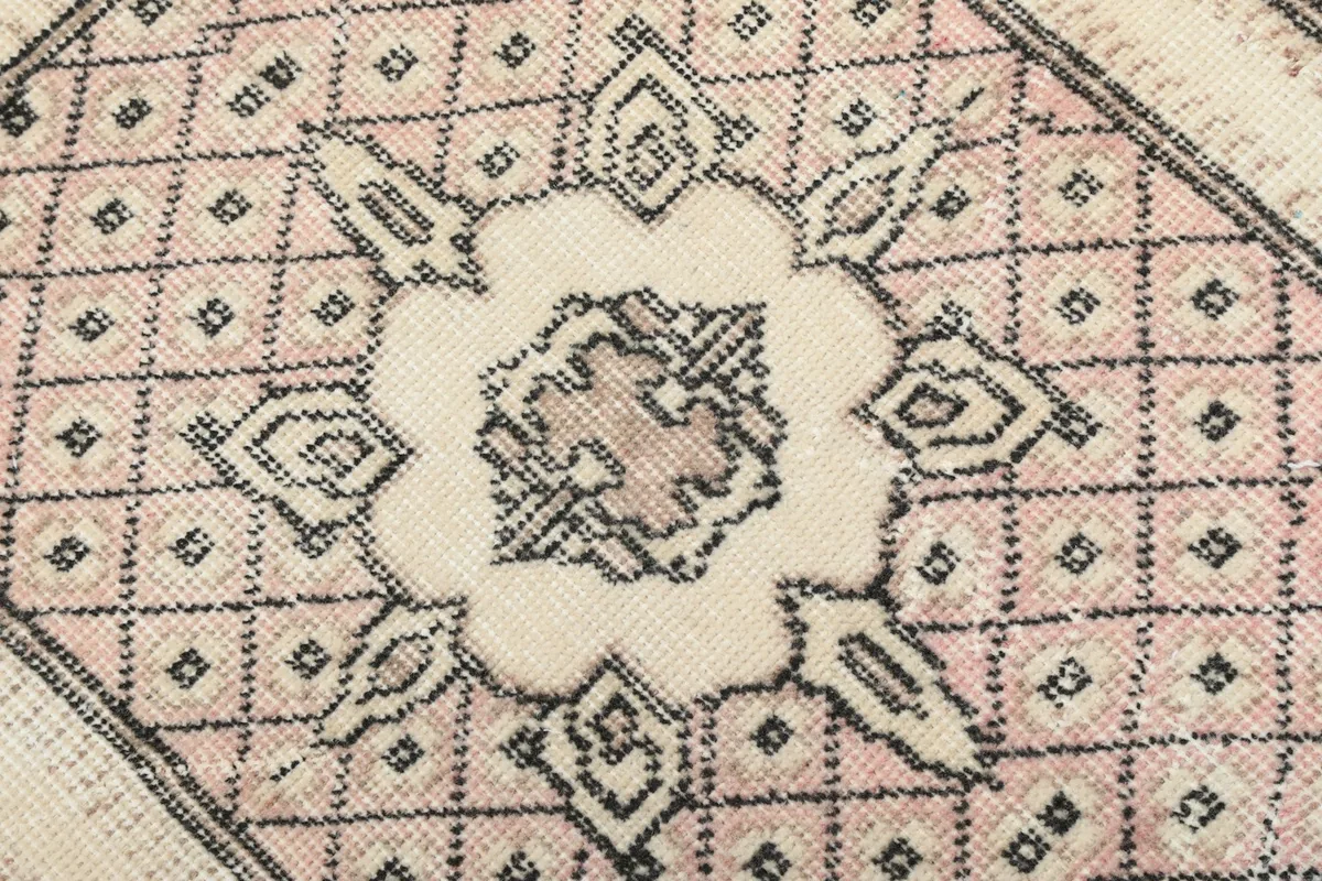 Detailed shot of the intricate geometric patterns within the ivory medallion and pink field