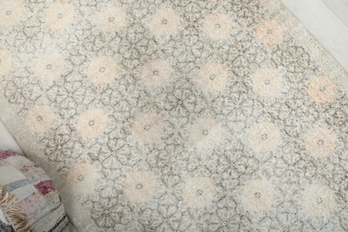 Diagonal view of the rug's surface, showing the repeating floral motifs and worn patina.