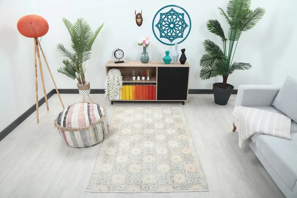 Vintage Anatolian rug in a living room setting, showing its size and color next to a gray sofa and pouf.