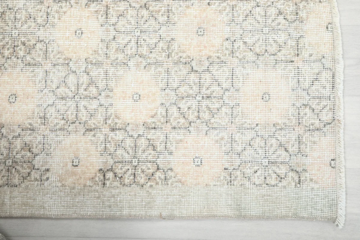 Overhead view of a section of the rug, highlighting the ivory and gray pattern with hints of rose.