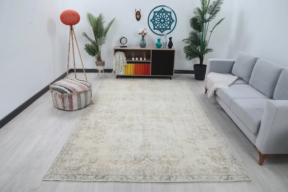 Large cream vintage rug laid out in a modern living room setting with a gray sofa