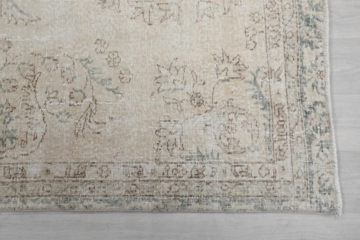 Close-up of the rug's border design, revealing faded gray and tan ornamental details