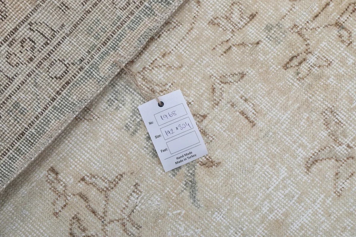 Tag displaying the rug's dimensions and origin, placed on the cream colored rug surface