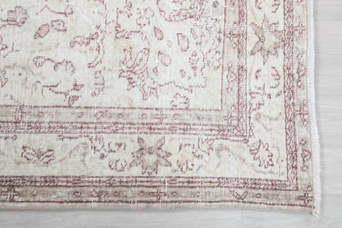 Detailed view of the corner border and floral motifs in faded rose and tan.