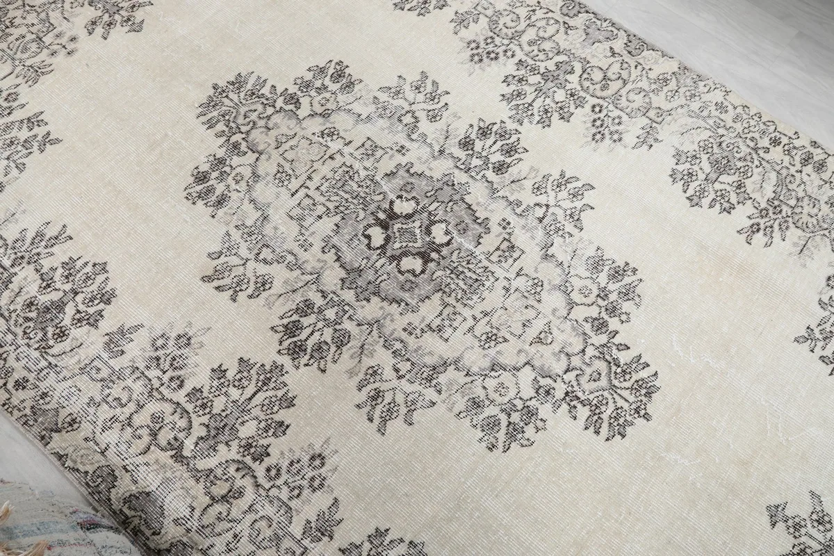 Overhead angle capturing the full design of the ivory and gray rug with its central medallion