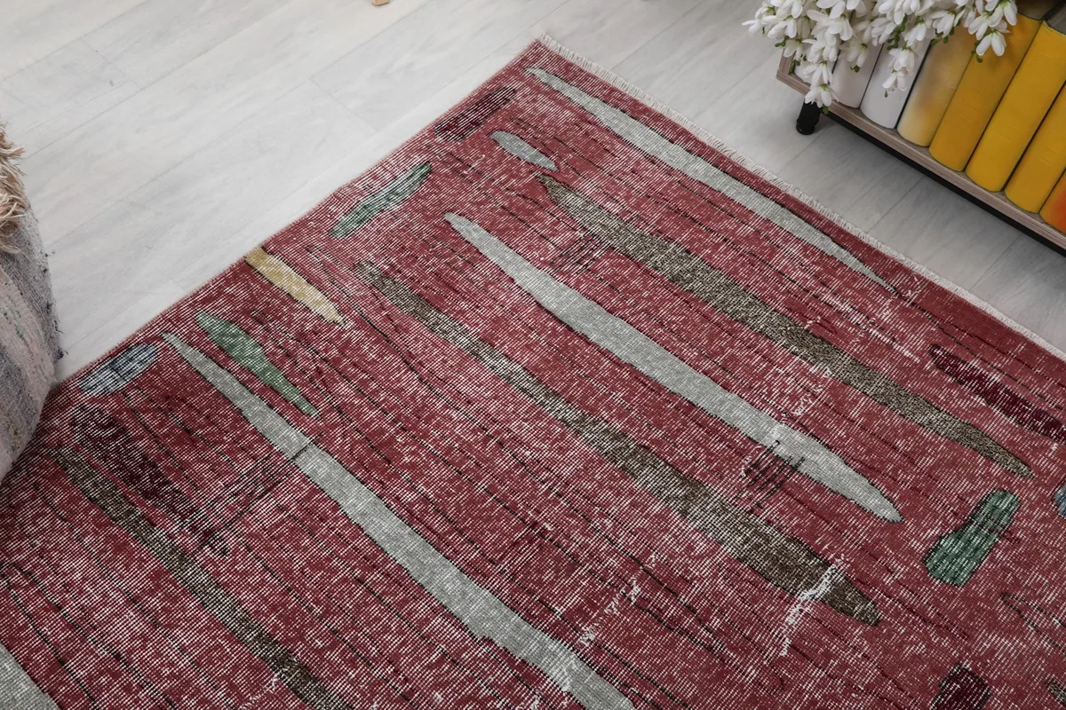 Corner view of the rug, showing the blend of rose, gray, and green colors in the abstract pattern.