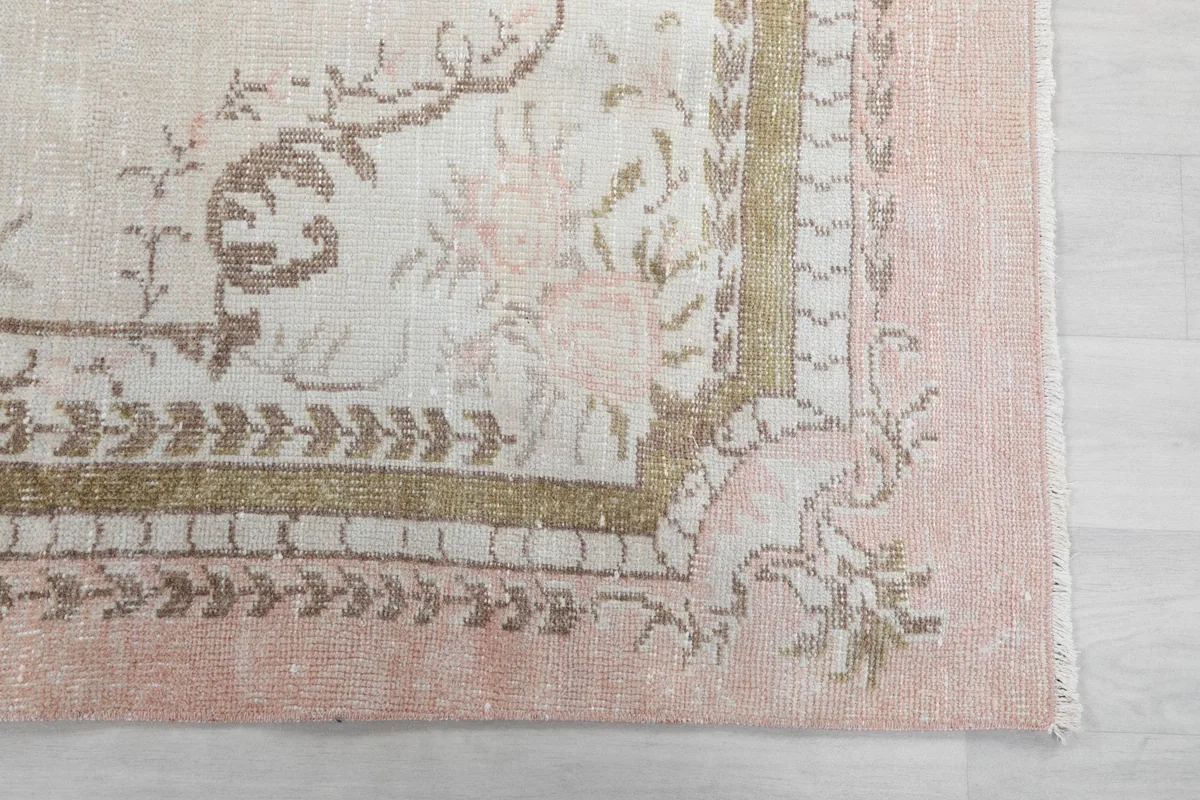 Close-up of the rose border and tan floral motifs at the corner of the rug