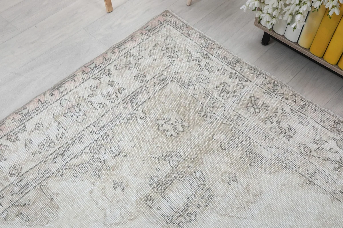 Corner view of the rug in the room, emphasizing the border details and overall faded appearance