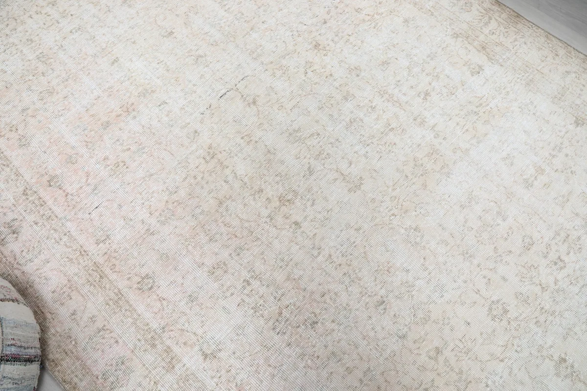 Overhead view focusing on the central area of the beige rug, revealing the overall distressed pattern.
