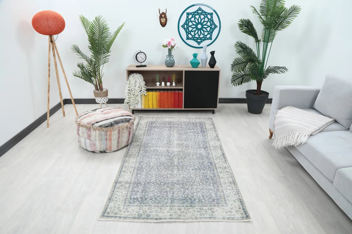 Vintage gray floral rug displayed in a bright room setting with modern furniture and plants