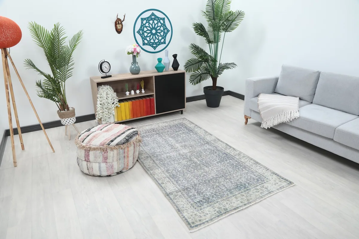 Overhead view of the small gray area rug accenting a contemporary living space with a sofa and pouf