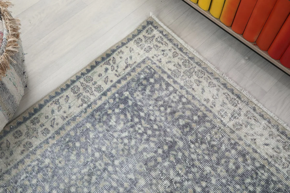 Corner detail of the rug showing the transition from the gray field to the cream border with floral designs