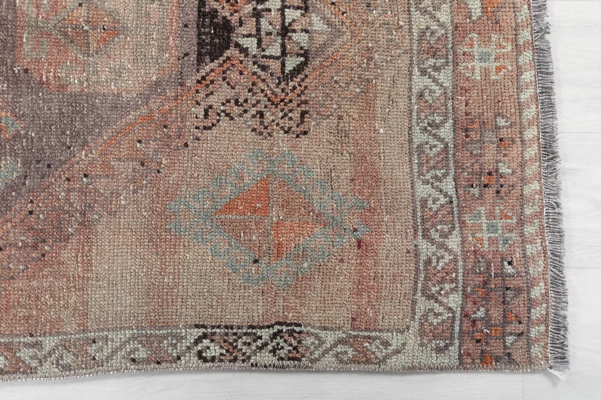 Detailed view of the rug's end, showing geometric motifs and border patterns