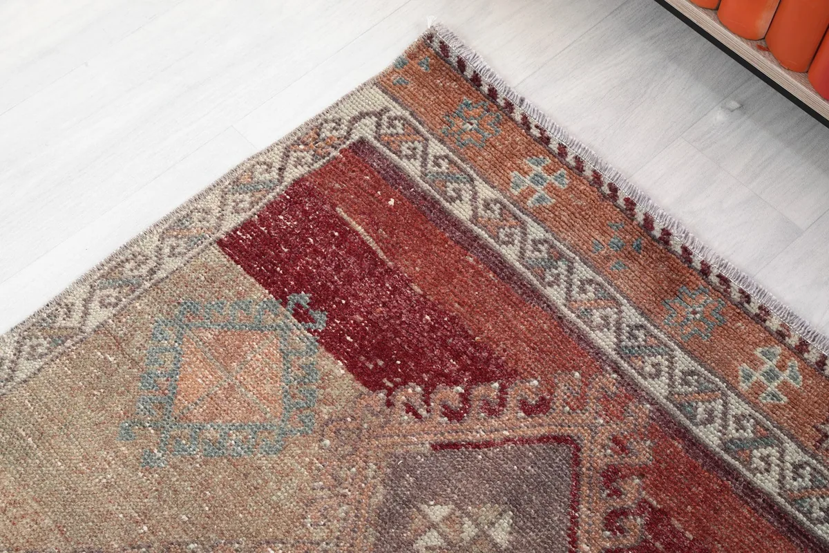 Detail of the rug's border and corner, with a mix of rust and beige tones