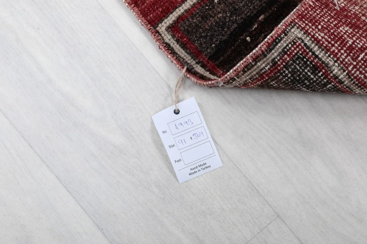 Corner of the rug with a product tag, indicating its origin and hand-knotted nature.