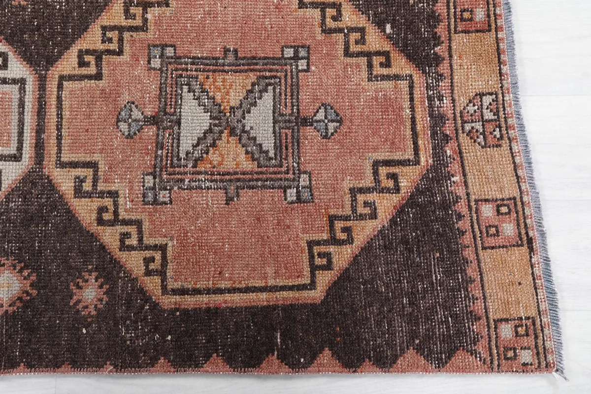 Detailed view of a rust-colored geometric medallion and the brown field