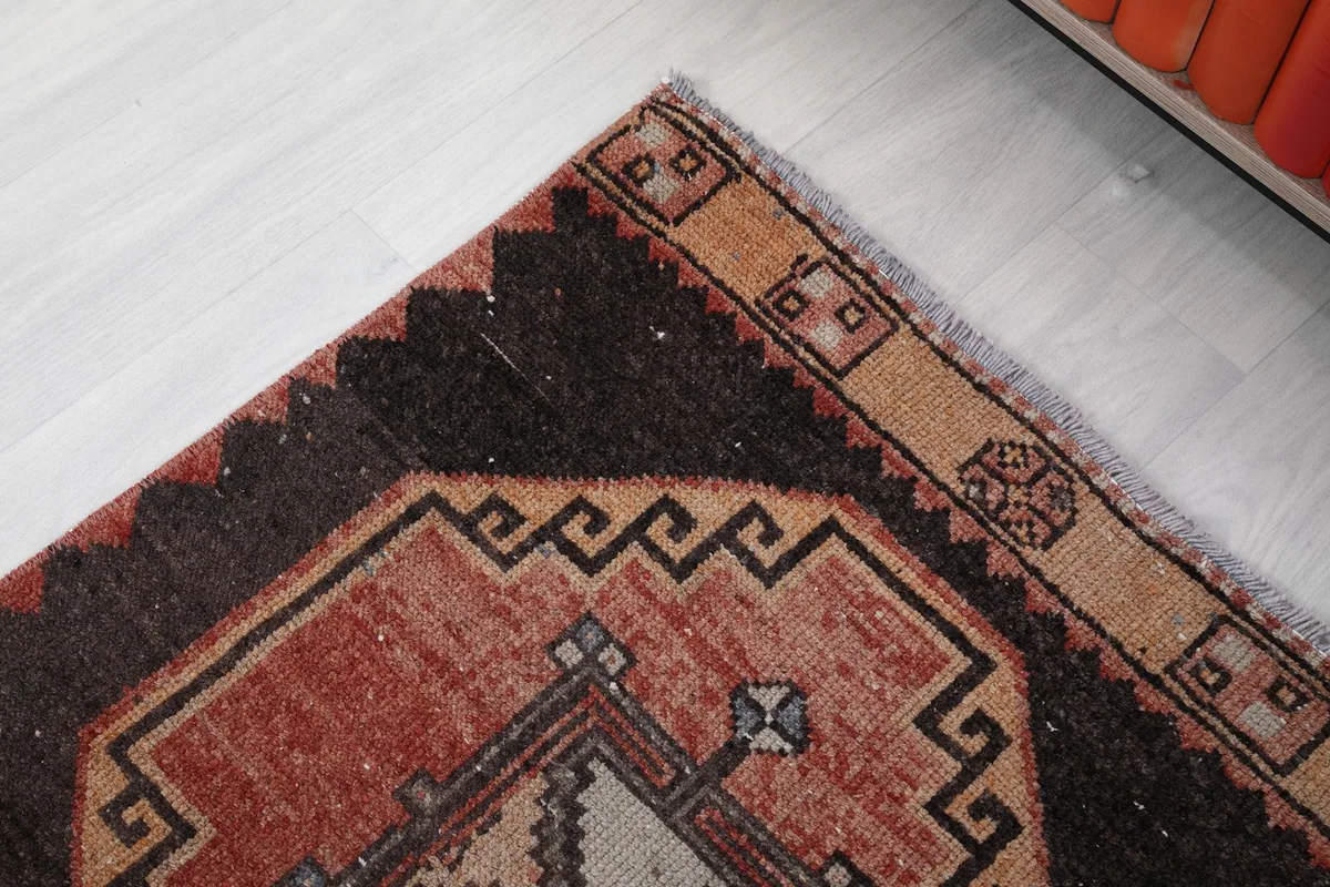 Detail of the rug's border and end, showing the tan outer band and brown field