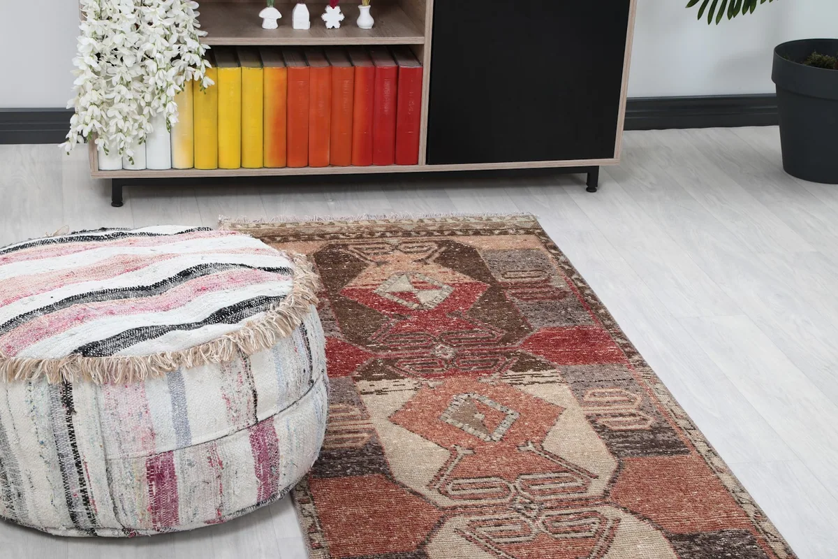 Close-up view of the runner rug's top end in a living space, next to a striped pouf and bookshelf