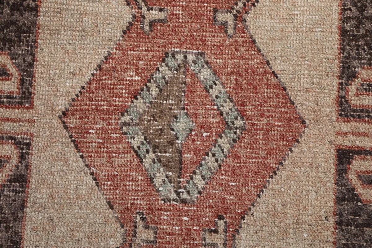 Close-up of a central diamond motif, showing faded colors and the intricate weaving