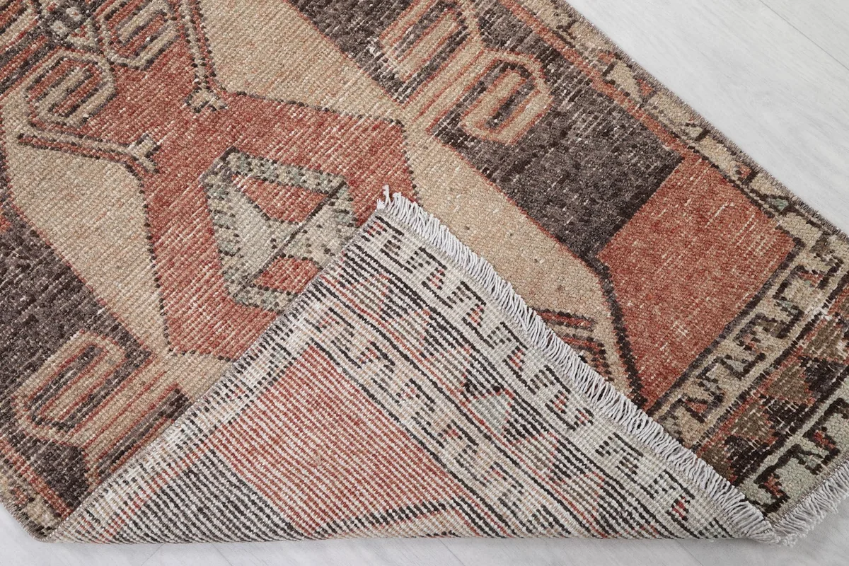 Corner of the rug folded back, revealing the reverse side and the cotton foundation