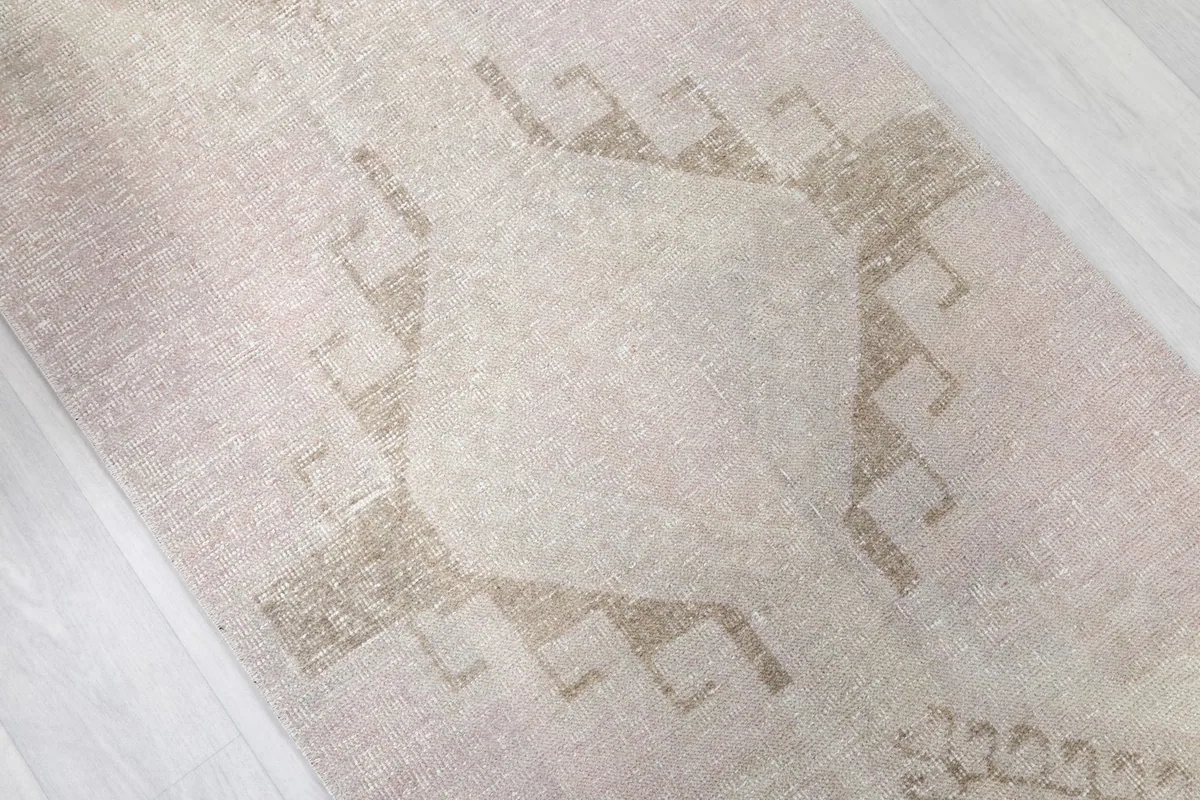 Close-up of a central geometric motif, showing the faded wool pile and subtle color variations