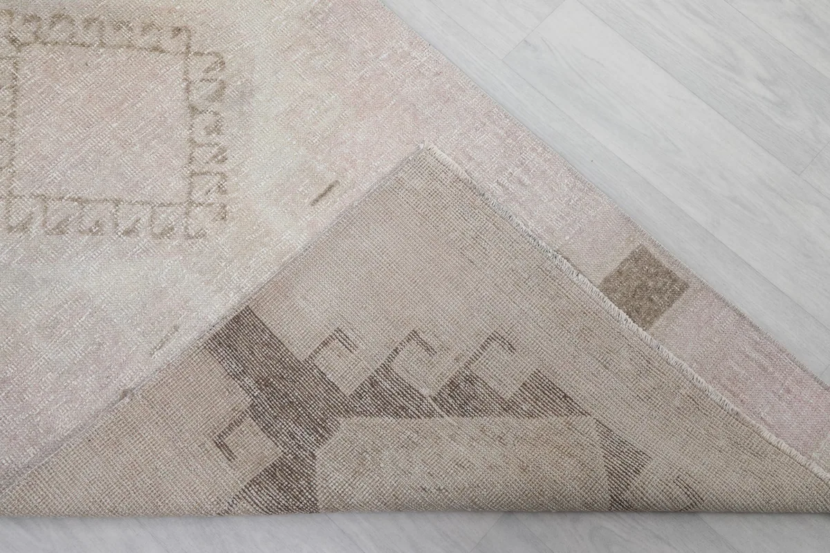Corner of the rug folded back to show the hand-knotted cotton foundation and reverse side